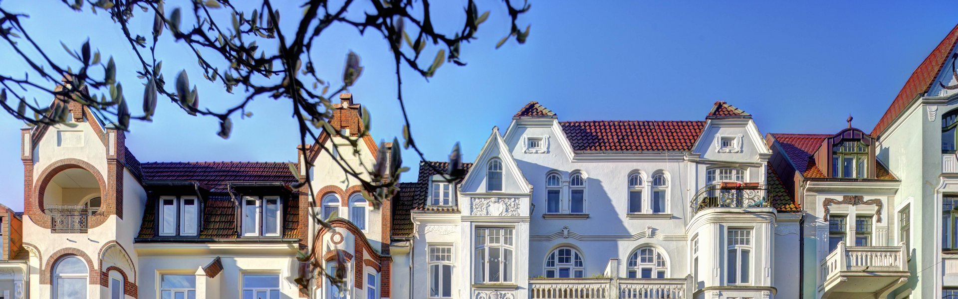 Auf der bunten Fotografie sieht man eine Reihe von Häusern. Die Häuser sind im Jugendstil gebaut.