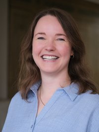 Eine junge Frau in hellblauer Bluse lächelt freundlich in die Kamera. 