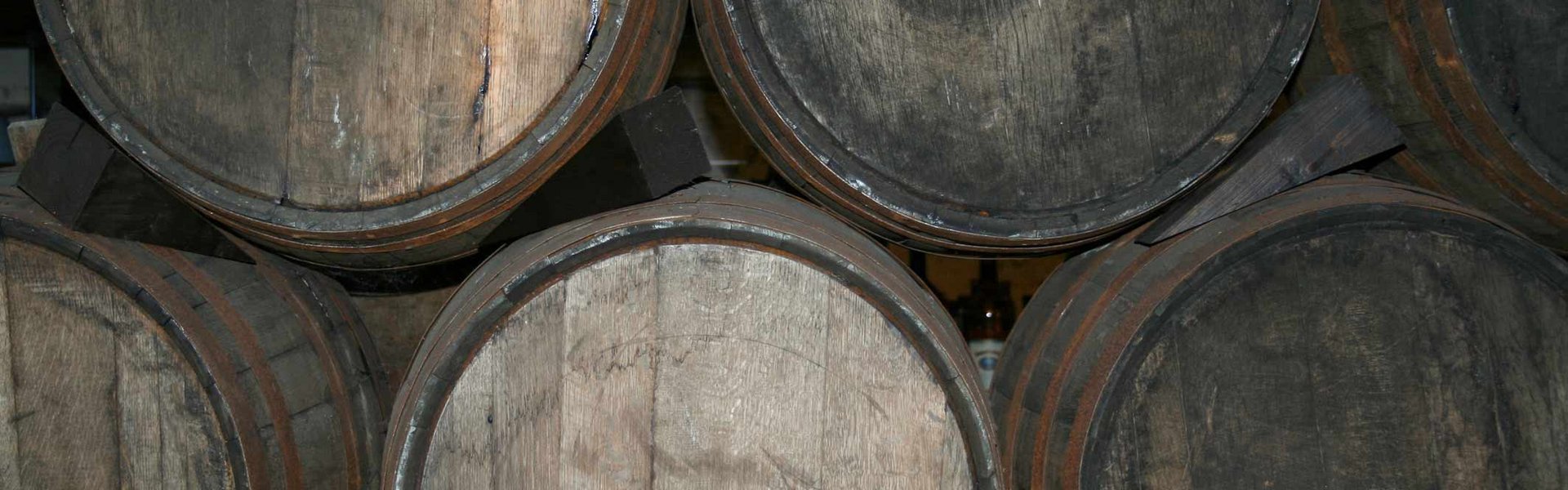 Im Keller des Flensburger Schifffahrtsmuseums liegen Rumfässer fein aufgestapelt. Hier ist eine Nahaufnahme von der Installation zu sehen. Man sieht sechs Fässer, die auf der Seite liegen, sodass nur ihre Böden zu sehen sind.