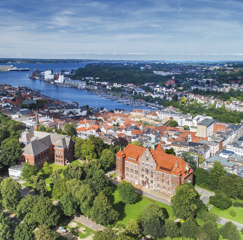 Heinrich-Sauermann-Haus og Hans-Christiansen-Haus er de to store huse foran. Tilsammen udgør de Museumsberg Flensburg. Billedet er taget højt oppe, derfor kan man også se andre huse og Flensburger Förde.