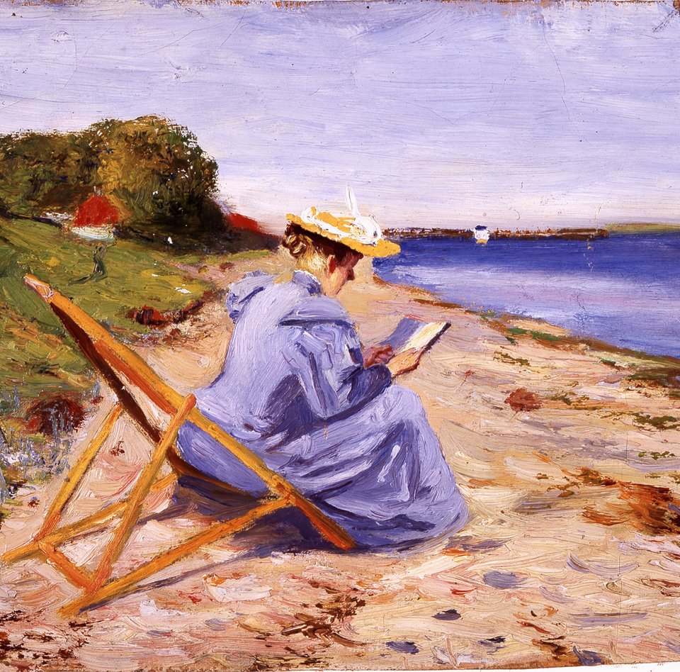 Eine Frau sitzt in einem Liegestuhl und trägt ein blaues Kleid mit einem Strohhut. Sie ist vorgebeugt und liest ein Buch. Hinter ihr sieht man den Strand und das Meer mit einem Boot. Links ist eine Wiese mit einem Haus und Bäumen.