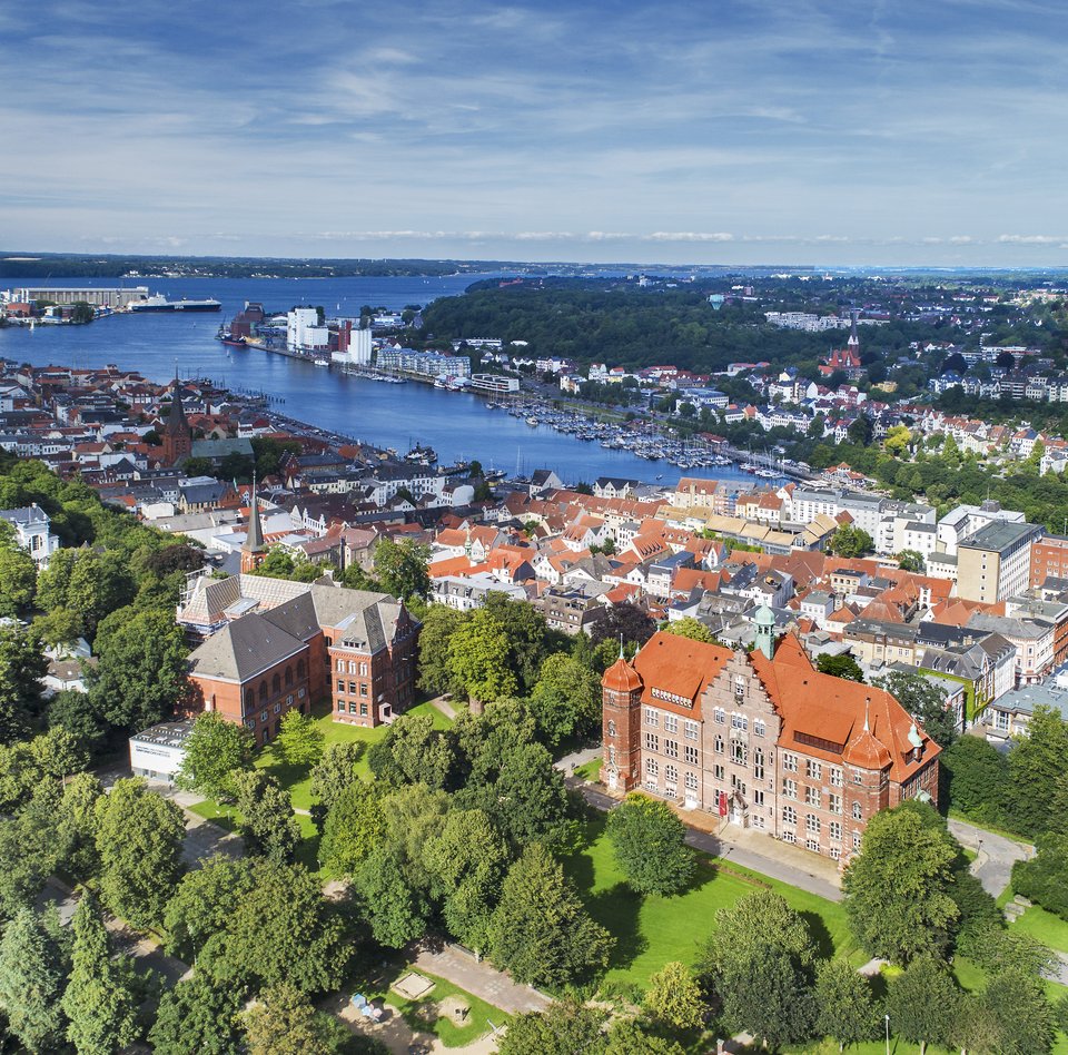 Das Heinrich-Sauermann-Haus und das Hans-Christiansen-Haus sind die beiden großen Häuser vorne. Zusammen sind sie der Museumsberg Flensburg. Das Foto wurde von weit oben gemacht, deshalb sind noch andere Häuser und die Flensburger Förde zu sehen. 