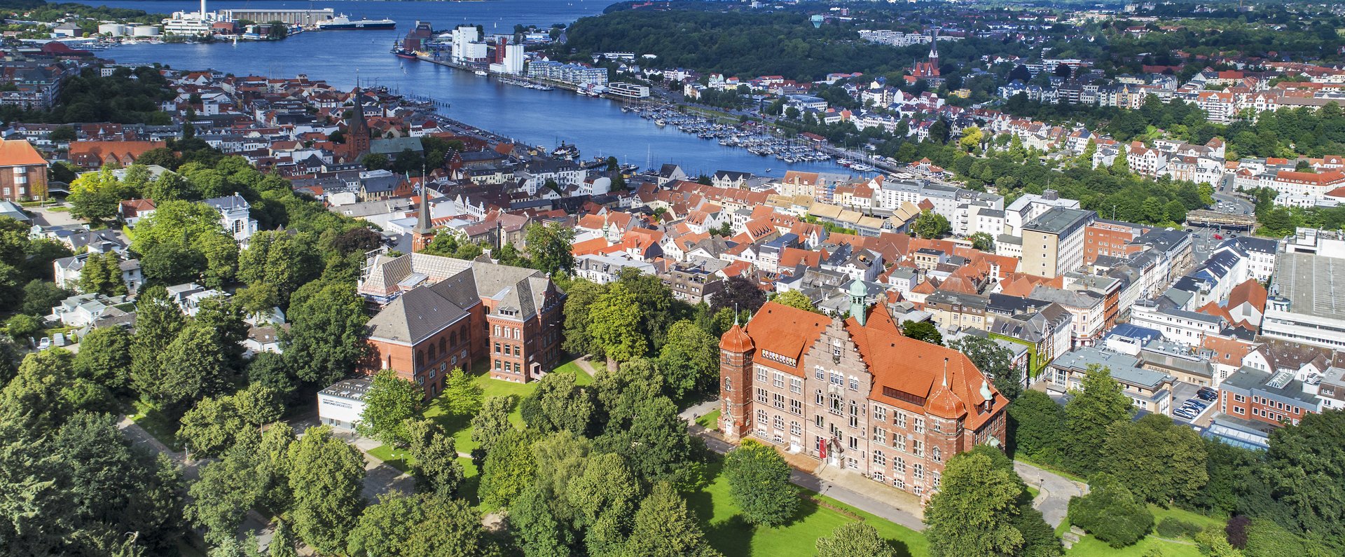 Das Heinrich-Sauermann-Haus und das Hans-Christiansen-Haus sind die beiden großen Häuser vorne. Zusammen sind sie der Museumsberg Flensburg. Das Foto wurde von weit oben gemacht, deshalb sind noch andere Häuser und die Flensburger Förde zu sehen. 