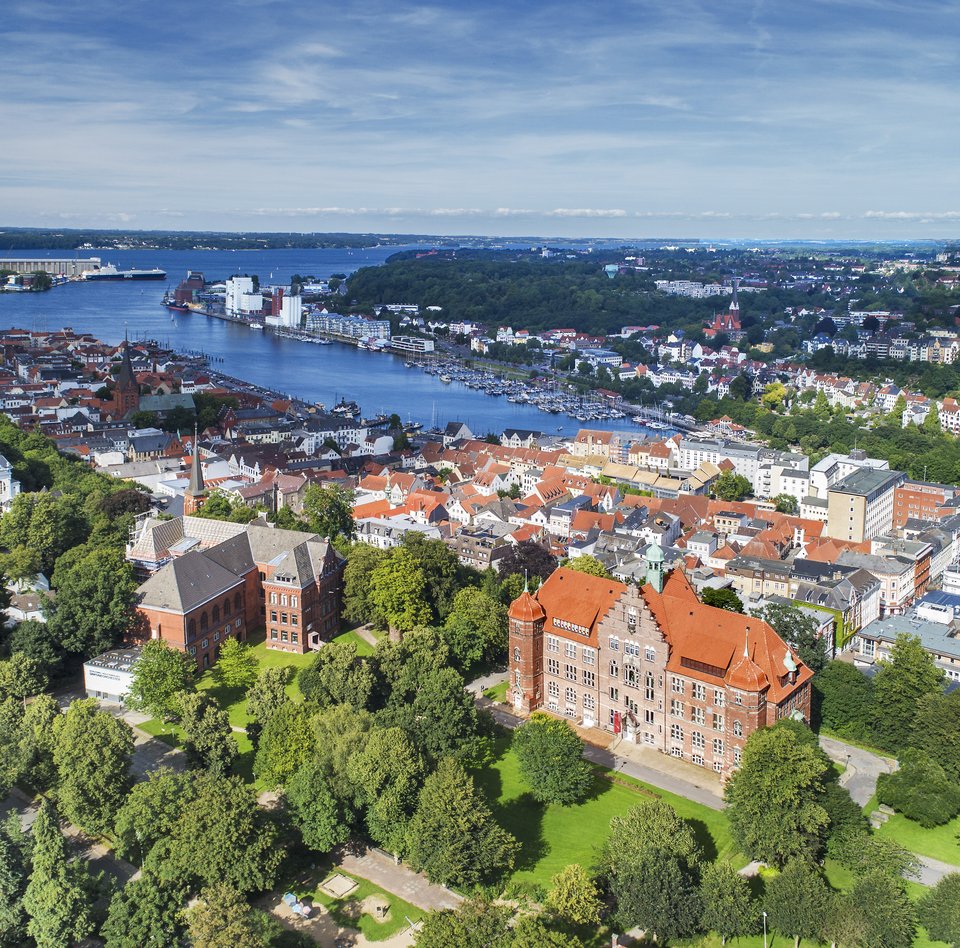Das Heinrich-Sauermann-Haus und das Hans-Christiansen-Haus sind die beiden großen Häuser vorne. Zusammen sind sie der Museumsberg Flensburg. Das Foto wurde von weit oben gemacht, deshalb sind noch andere Häuser und die Flensburger Förde zu sehen. 