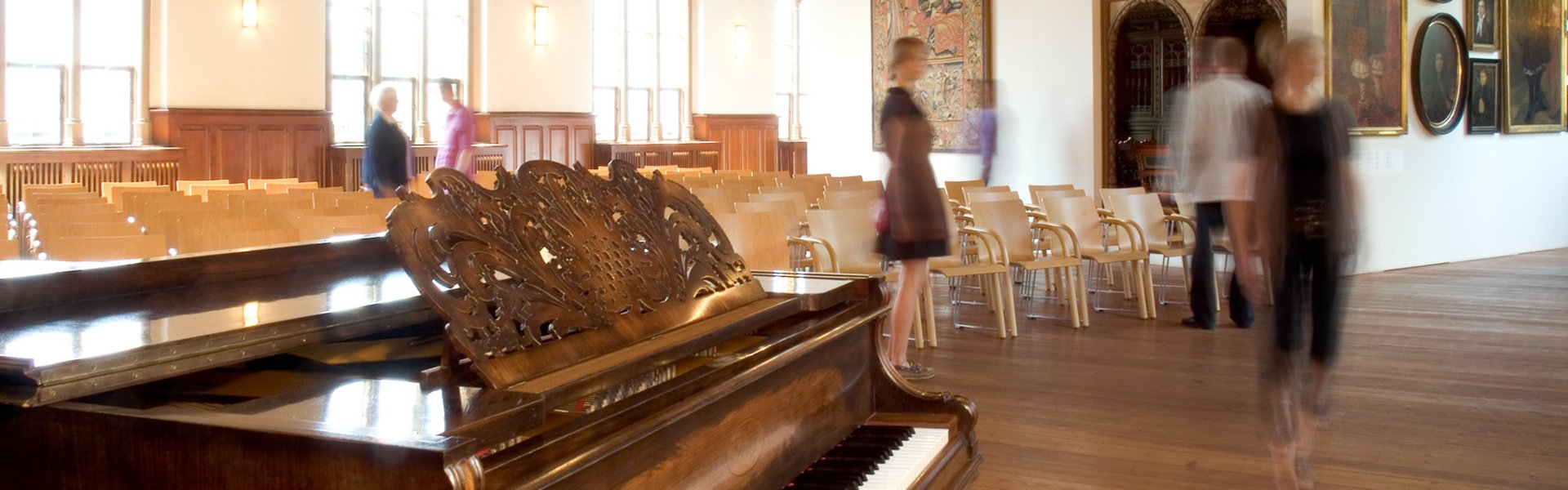 In der Aula des Museumsberg Flensburg finden verschiedene Veranstaltungen statt. Im Vordergrund steht ein Klavier, das für Konzerte genutzt wird. Dahinter sind viele Stühle für die Gäste zu sehen.