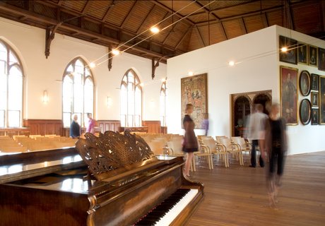 In der Aula des Museumsberg Flensburg finden verschiedene Veranstaltungen statt. Im Vordergrund steht ein Klavier, das für Konzerte genutzt wird. Dahinter sind viele Stühle für die Gäste zu sehen.